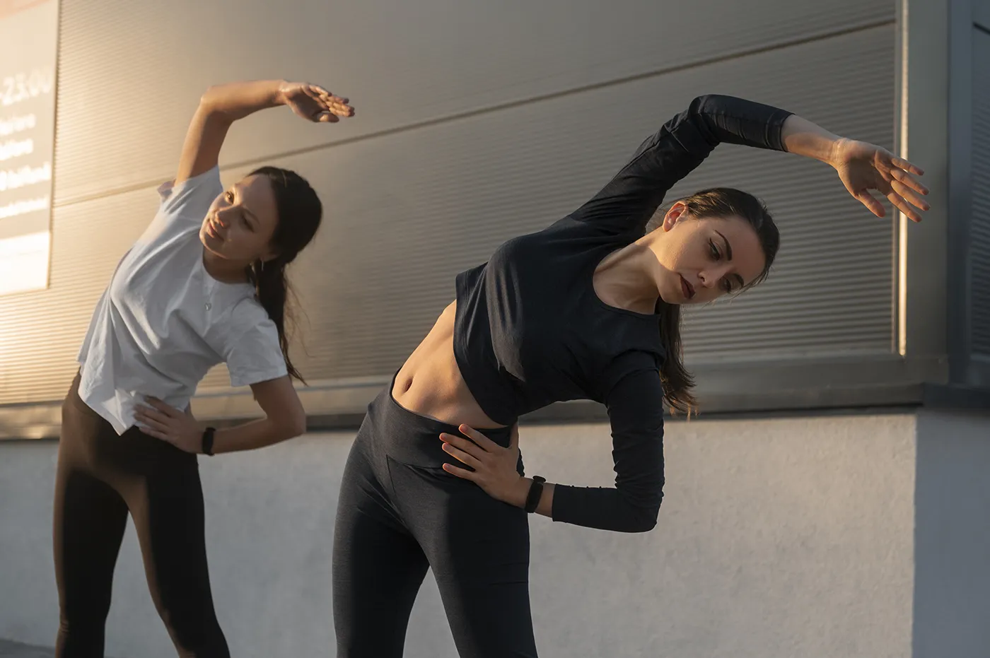 Two women warming up with side stretches before training — back to sports season tips by Blair Chiropractic & Massage Therapy.