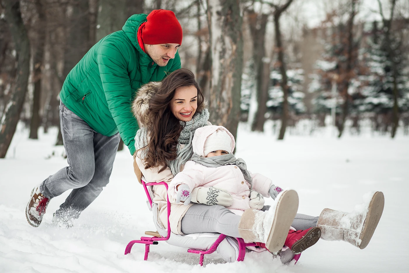 Parents pulling sled with child while preventing typical injuries from winter by Blair Chiropractic & Massage Therapy