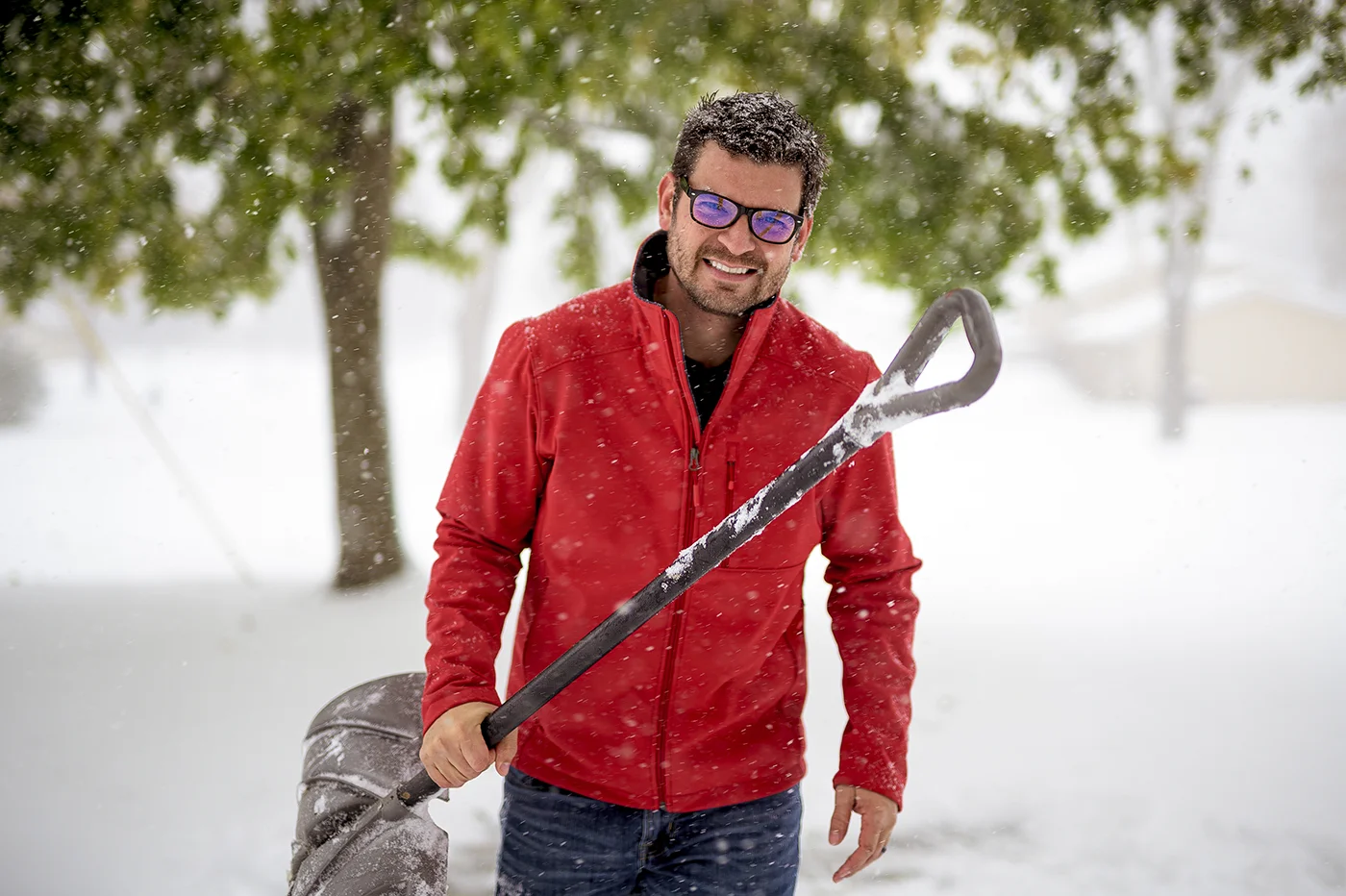 Man shovelling snow during snowfall for snow shovelling safety by Blair Chiropractic & Massage Therapy