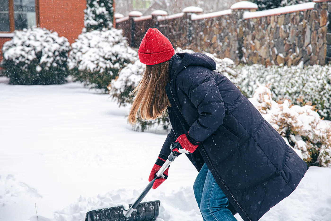 Woman clearing backyard snow for snow shovelling safety by Blair Chiropractic & Massage Therapy
