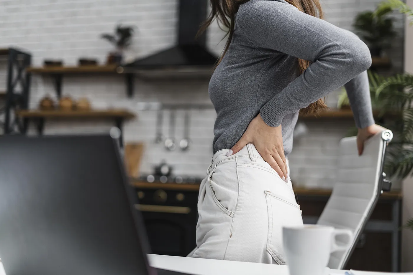 Woman experiencing lower back pain at home, chiropractic for sciatica care at Blair Chiropractic & Massage Therapy